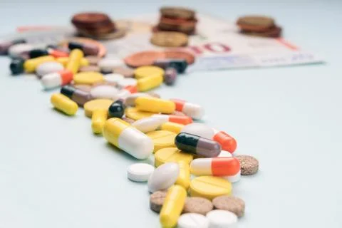 Path of tablets of different sizes and colored capsules leads to paper bankno Stock Photos