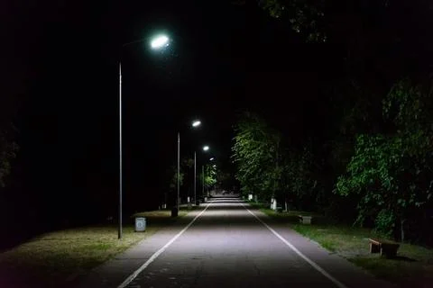 Path through city park at night with street lamps Stock Photos