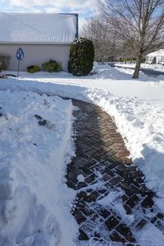 Path through high snow exposing brick sidewalk in front of a house Stock Photos