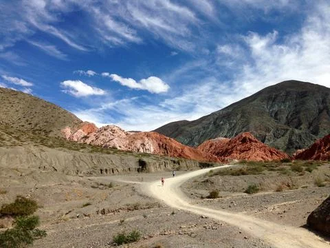 Path through red, green landscape with blue sky and white clouds Stock Photos