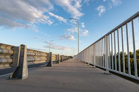 Path walking along road sheltered by barriers and grate Фото