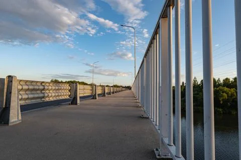 Path walking along road sheltered by barriers and grate Фото