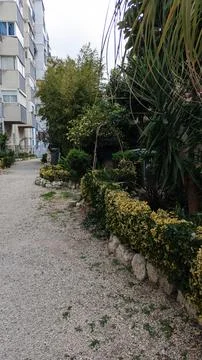 A path of white small stone through a mini park near tall houses Stockfoto's