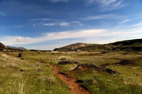 A path winding through a grassy high desert landscape with hills in the distance Stock Photos