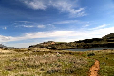 A path winding through a grassy high desert landscape with hills in the distance Stock Photos