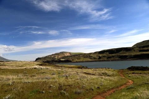 A path winding through a grassy high desert landscape with hills in the distance Stock Photos