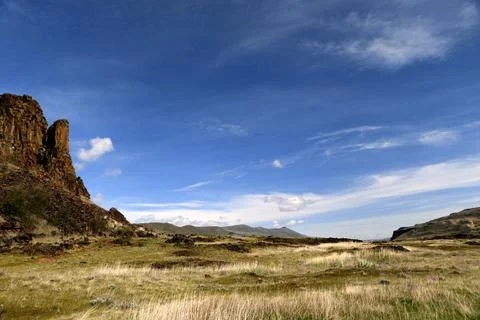 A path winding through a grassy high desert landscape with sheer, rocky, cliffs, Stock Photos