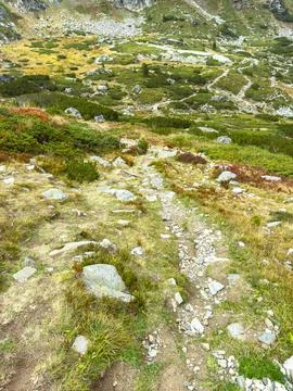 Path winding through green hills in a mountainous area during daytime Stock Photos