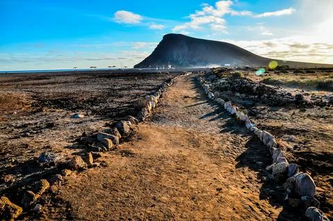 A path winds through a desert with a mountain in the background Stock Photos