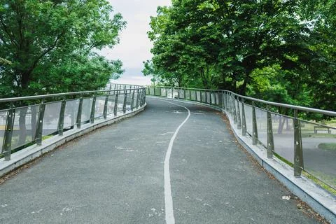 A path winds through a green park area in the daytime with trees lining bot.. Stockfoto's