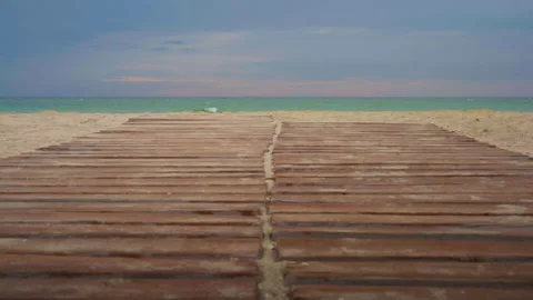 A path of wooden planks on a sandy beach leading to the sea against the Stock Footage 203000302