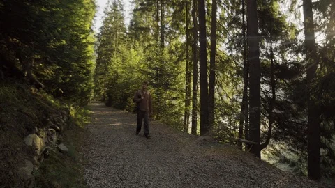 The path of a young man, a tourist walking along a beautiful road to the forest Stockbeeldmateriaal 90098631