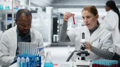 Pathologist examining biopsy slide while colleague documents diagnostic findings Stock Footage 327417849