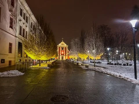 Pathway lined with trees and Capuchin monastery during winter night in city Stock Photos