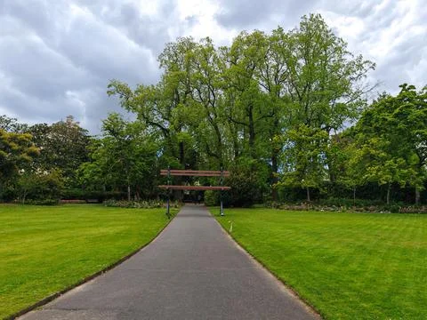 Pathway in park with large bench and green trees Foto stock