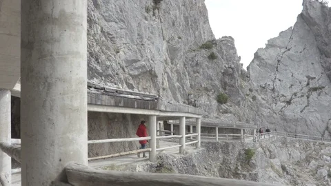 Pathway through the rocky mountain with the walking person in the red jacket Stock Footage 89619716