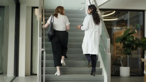 Patient and doctor talking while climbing staircase in hospital Stock Footage 105605853