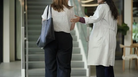 Patient and doctor talking while climbing staircase in hospital Stock Footage