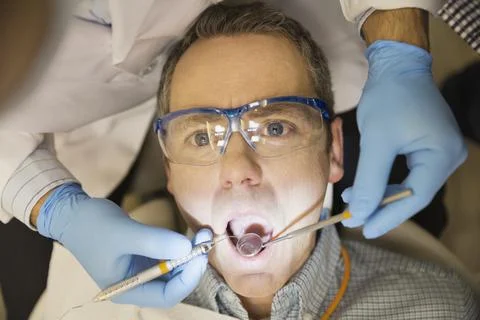 Patient with angled mirror and scraper in mouth Stock Photos