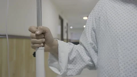 A patient boy hand holding IV medical liquid infusion bag pole stand Stock Footage