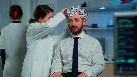 Patient with brainwave scanning headset sitting in brain study lab Video stock 148989013