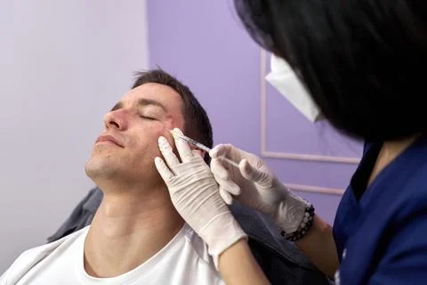 Patient closing eyes while getting a rejuvenation treatment with botox injection Stock Photos