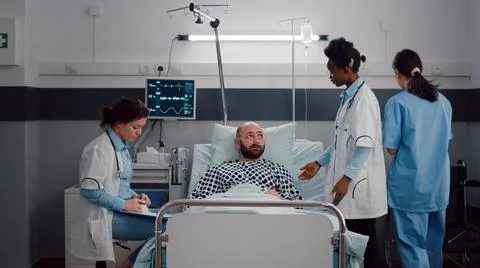 Patient discussing with doctors while resting in bed during medical recovery Stockfoto's