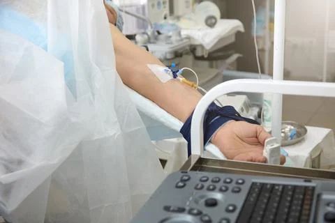 Patient during surgery on the operating table with a catheter in his hand Stock Photos