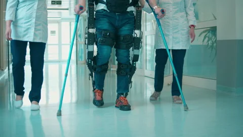 A patient in the exoskeleton is walking with nurses' help Video stock 158153328