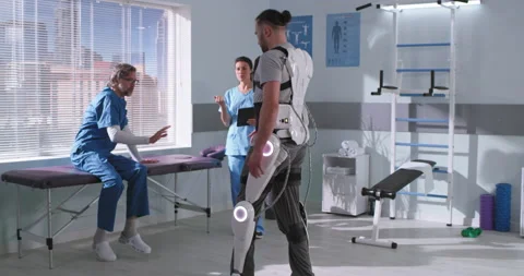 Patient in exoskeleton walking towards doctors Stock Footage 154984535