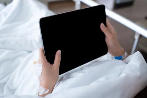 Patient hand using digital tablet while lying on bed in hospital Stock Photos