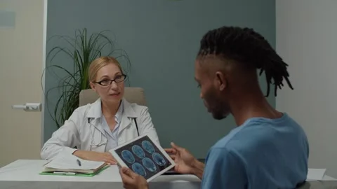 Patient looking at MRI digital image on tablet, asking doctor indoors Stock Footage 165648692