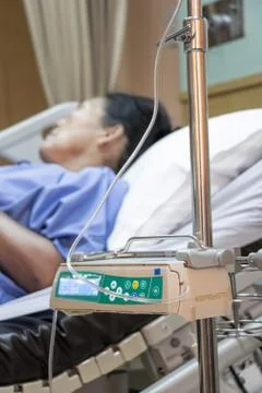 The patient is lying on a bed beside automatic infusion device Stock Photos