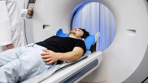 Patient lying on CT scanner table, preparing for tomography procedure, with.. Stock Photos