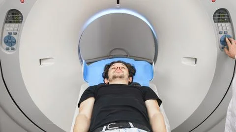 Patient lying on CT scanner table, preparing for tomography procedure, with.. Stock Photos