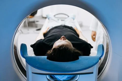 Patient lying on examination table inside CT scanner, surrounded by medical.. Stock Photos