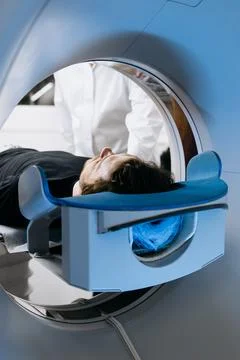 Patient lying on examination table inside a CT scanner, surrounded by medic.. Stock Photos