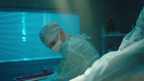 Patient lying unconscious on the bed while doctors perform surgery Stock Footage 283146719