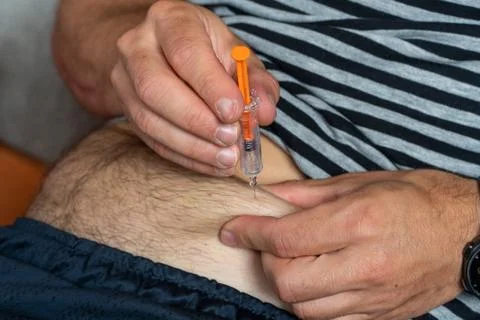 Patient make a subcutaneous injection by single use syringe with needle into  Stock Photos