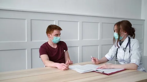 Patient in the mask measures the temperature under the supervision of physician Stock Footage 127478181