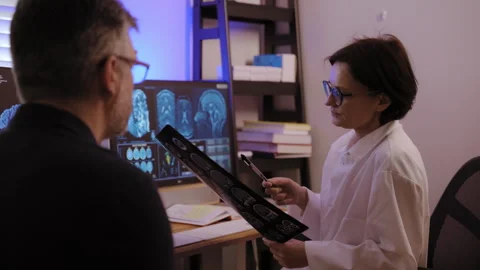 Patient MRI scan is analyzed by doctors with patient to diagnose brain Stock Footage 303881611