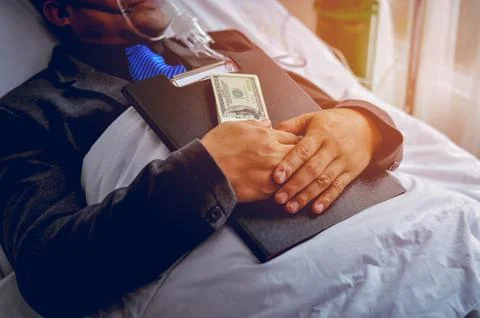 The patient sleeps in the bed while the hand is still working on the business 写真素材