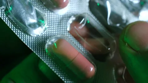 Patient taking medication from blister pack under green light Stock Footage 311943763