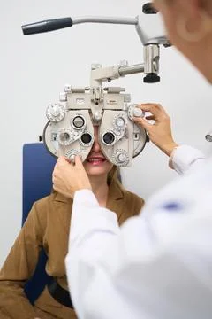 Patient undergoing eye exam using phoropter at clinic Stock Photos