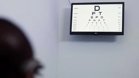 Patient undergoing vision test screening visual acuity using a digital eye chart Stock Footage 346770298