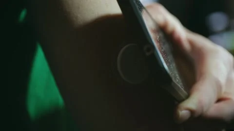 Patient using nfc smartphone to scan glucose monitor sensor Stock Footage 296552012