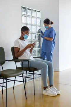 Patient using smartphone while sitting in a waiting room. Stock Photos