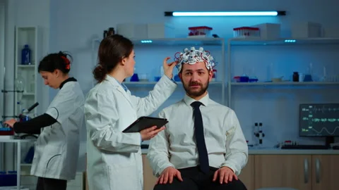 Patient wearing brainwave scanning headset discussing with neurological Stock Footage 148988620