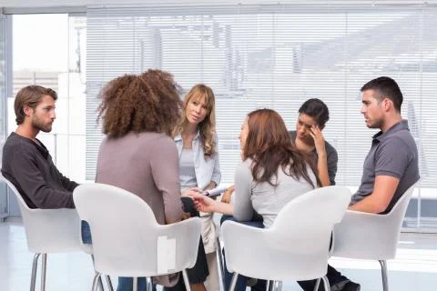Patients around therapist in group therapy session Stock Photos