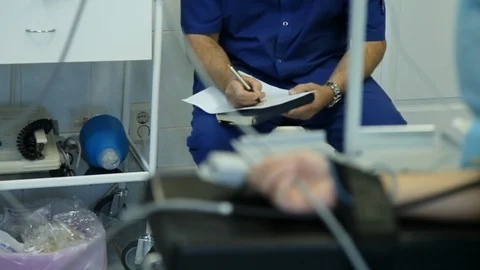 Patient's hand under anesthesia with a sensor on his finger and a doctor filling Video stock 127301755